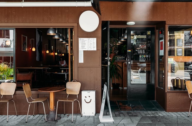 The front of ADJØ cafe with big open windows and glass doors.