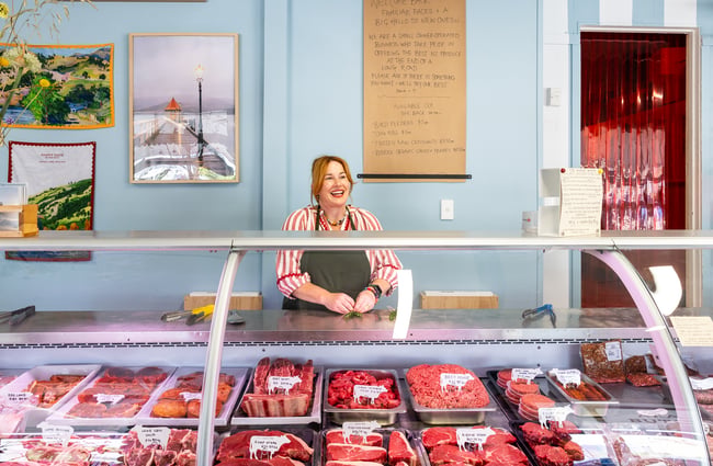 Owner Julia standing in front of local meat display at Akaroa Butchery & Deli