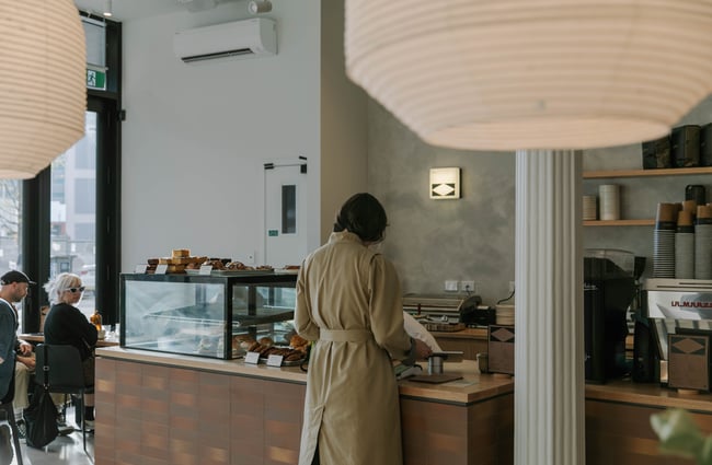 A customer in a trench coat ordering at the counter.