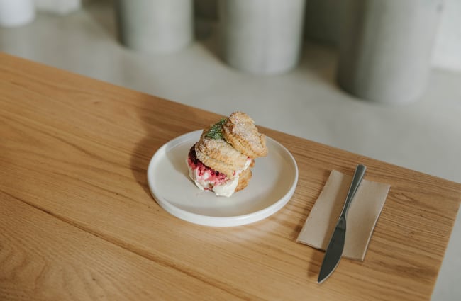 A close up of a jam and cream scone.