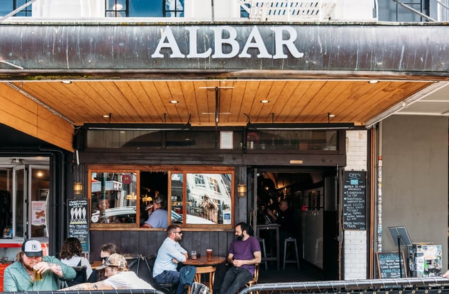 People sat outside Albar drinking beer at tables.