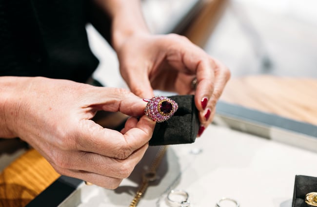Two hands holding a beautiful pink diamond ring.