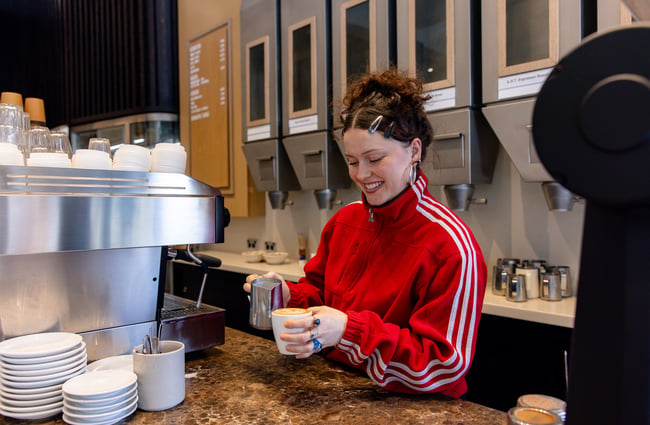 Smiling barista pouring coffee at Allpress Auckland Roastery