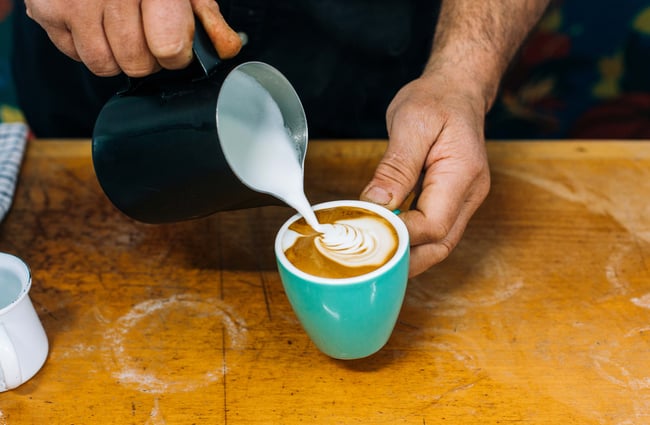 Barista pouring milk into a coffee cup at Aloha Friday, Porirua.