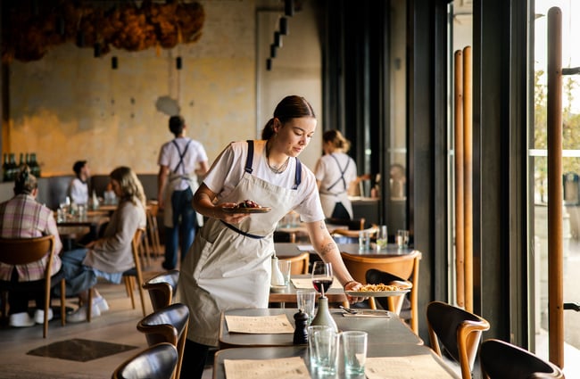 A staff member placing a plate of food on a table.