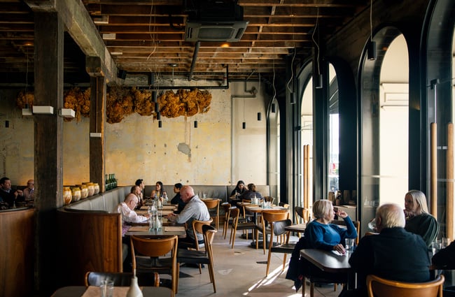 Customers dining inside a high ceilinged restaurant.