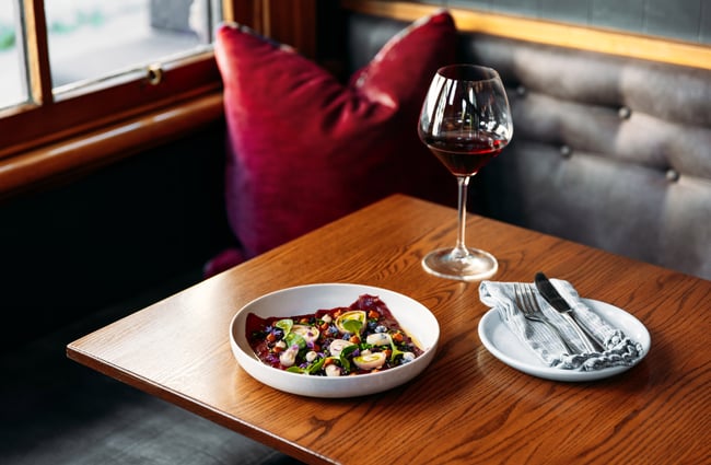 A plate of food and a glass of red wine on a table.