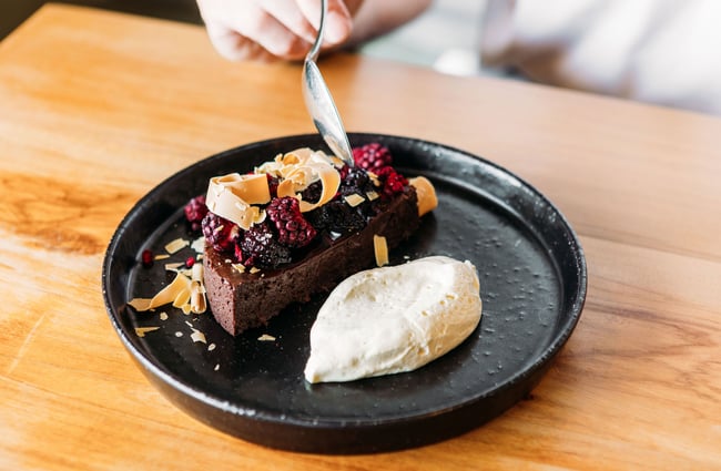 A chocolate mousse-type dessert dish topped with berries and served with a scoop of ice cream.