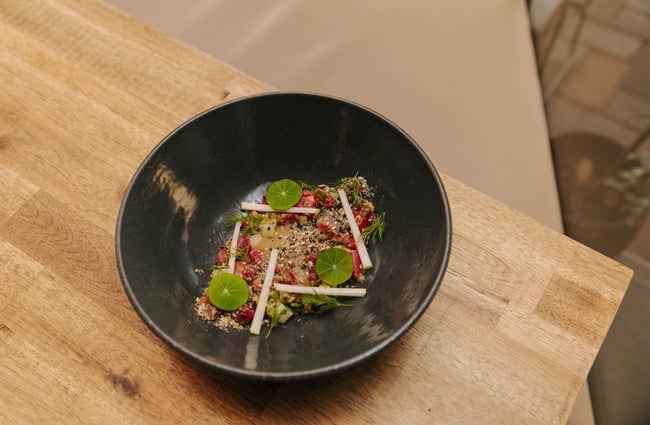 Food in a bowl on a wooden table at Arden.