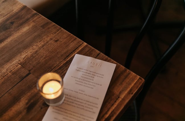 Arden menu on a table with candle.