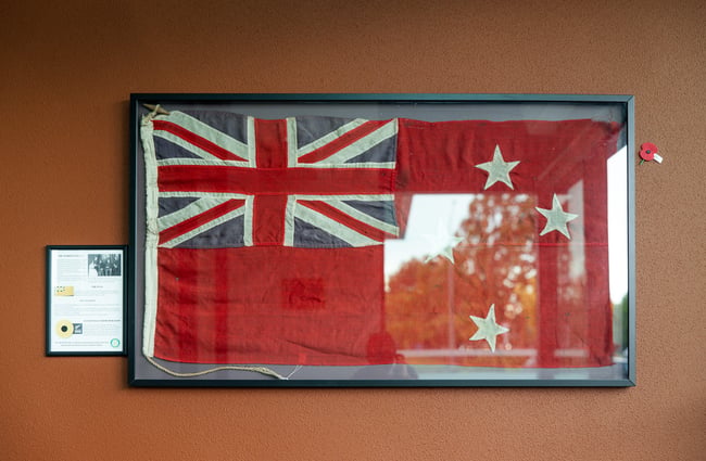 An old red and blue flag framed on a wall.