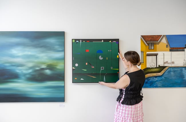 Gallery owner hangs a piece of art on the walls at Ashe.