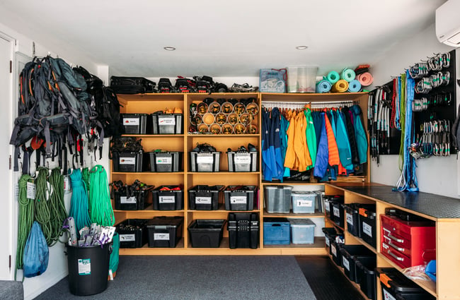 Backpacks hanging on the wall, jackets on a rail and other equipment on shelves at Aspiring Guides.