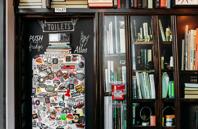 Books in black shelves inside a bar.