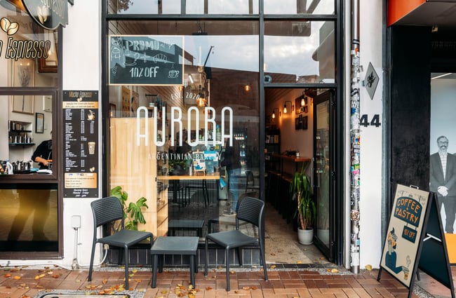Exterior of Aurora Argentinian Bakery with signs outside.