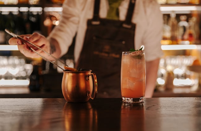 Man placing a lemon slice on top of a drink at Austin Club in Christchurch.