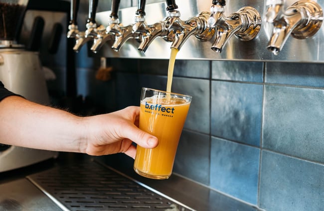 Hand holds a pint of beer being poured from a tap at b.social, Wānaka.