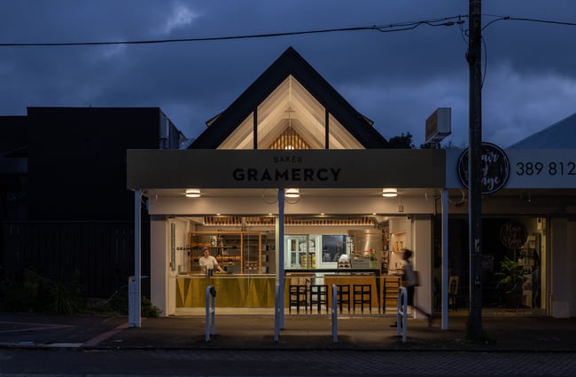 The shop frontage with lights on inside, dark early morning sky outside.