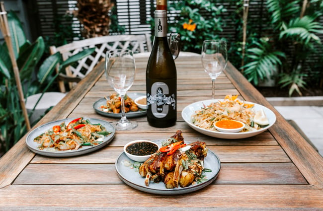 Table with dishes and bottle of wine at Bandung Café, Auckland.