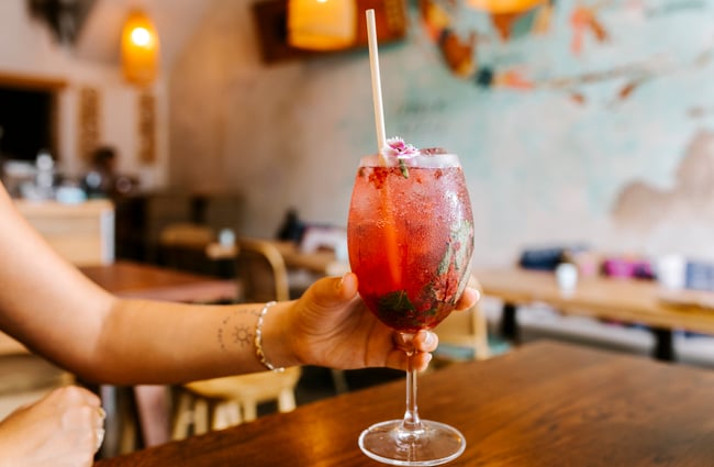 Woman holding a red cocktail from Bandung Café, Auckland.