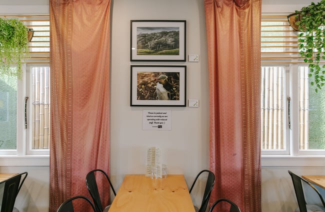 Peach coloured curtains hanging next to a table and chairs.
