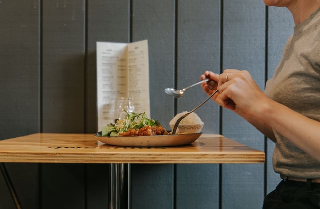 A female customer sitting at a table with a plate of Thai food.
