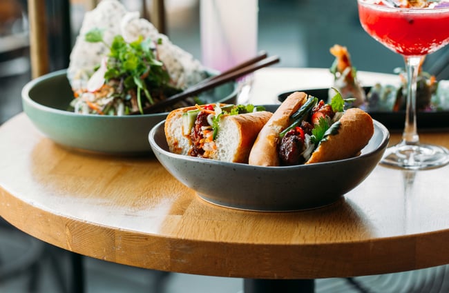 A bread roll filled with meet and vegetables served in a grey bowl.