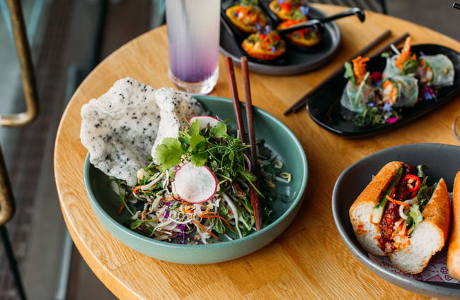 Four different meals planted up and served on grey and blue plates with chopsticks.