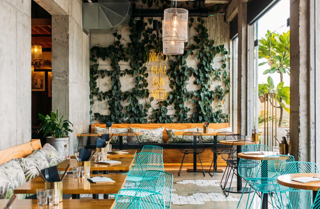 Bright blue wire chairs with wooden tables inside the Banh Mi restaurant.