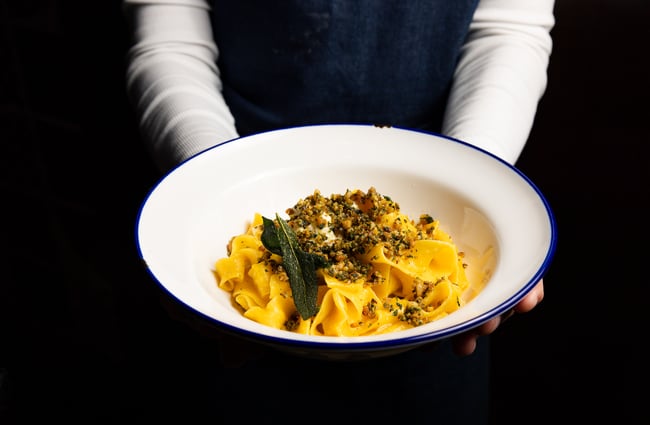 Wait staff holding a plate of pasta at Bar Franco.
