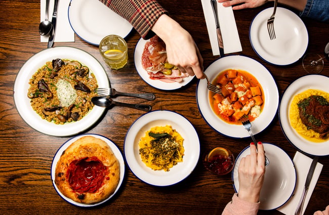 Multiple food dishes on the table with drinks at Bar Franco.
