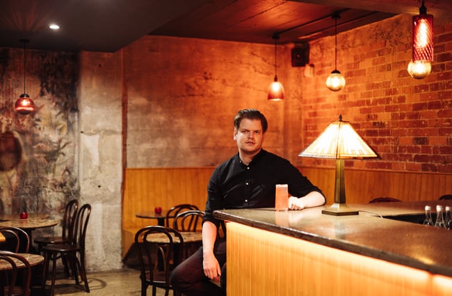 A man looking at camera holding a cocktail.