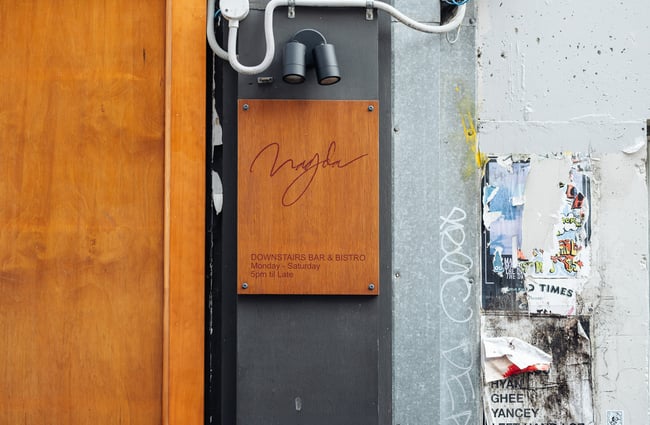 A wooden sign with information on Bar Magda.
