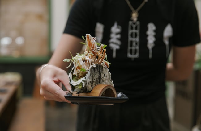 A hand holding a large sushi roll.