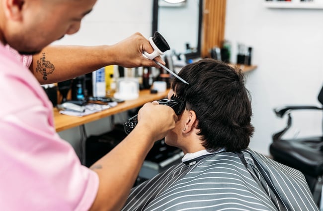 A close up of a man receiving a hair cut.