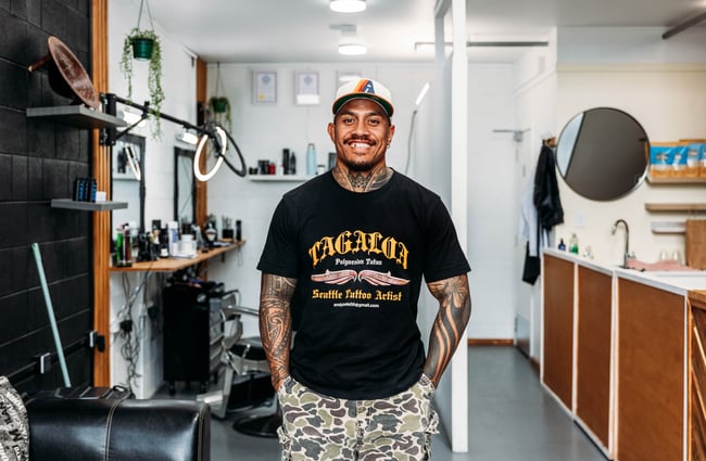 A tattooed man smiling to camera.