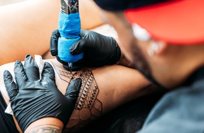 A close up of an arm being tattooed.