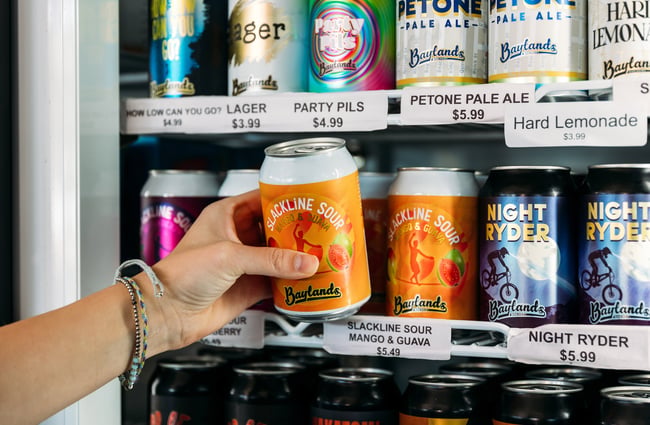 Someone grabbing a cold can of craft beer from the fridge at a taproom
