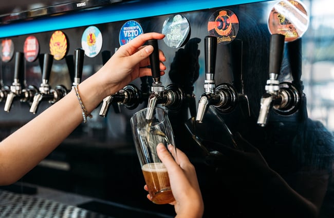 Bartender filling up a pint of craft beer at taproom
