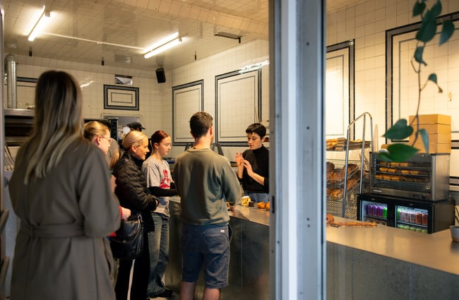 Customers waiting in line inside a bakery.