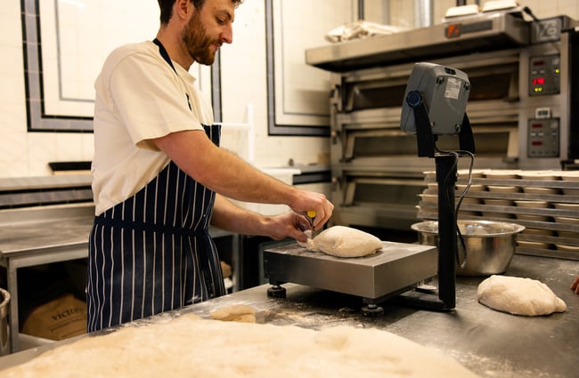 A man rolling out a loaf of bread dough.