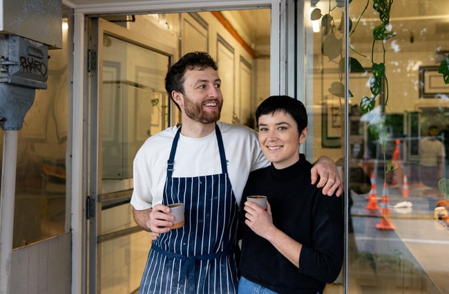 A man and woman looking at the camera outside their afe.