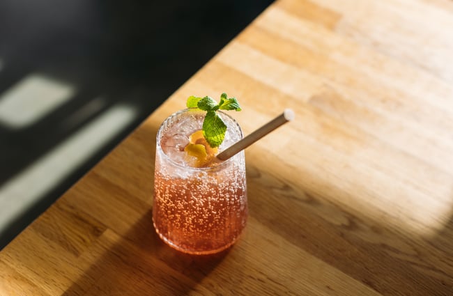 A close up of a fizzy drink decorated with a flower on a table.