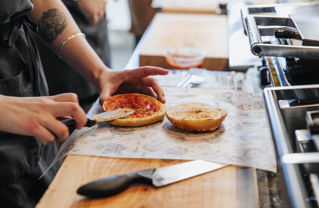 Jam being spread onto a bagel.