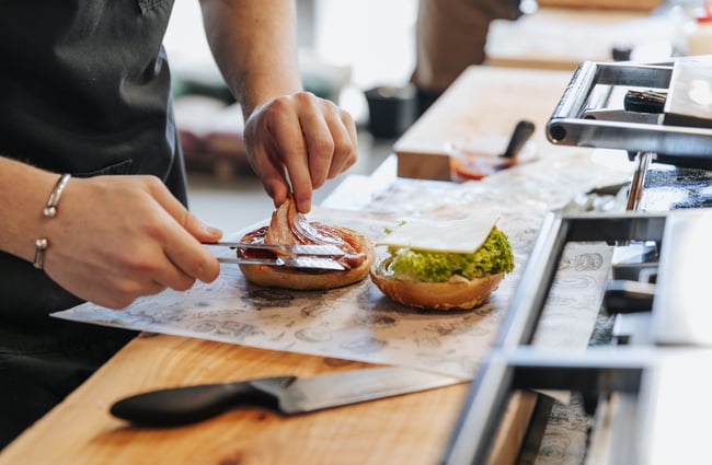 Bacon being added to a bagel.
