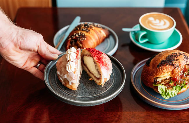 Donut on plate being placed on table at Belen Plant Bakery in Petone