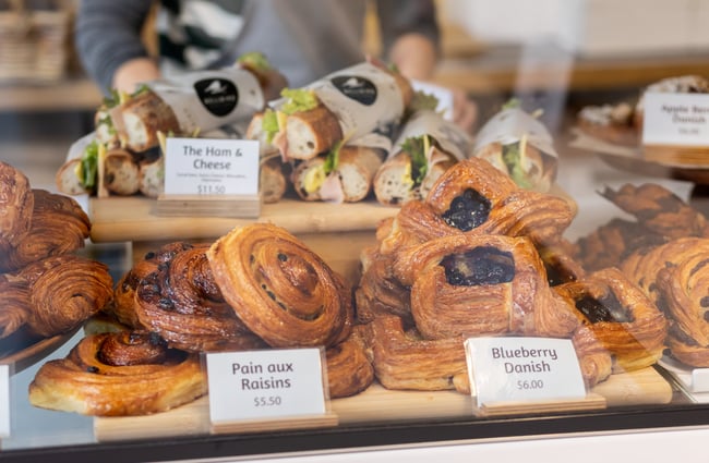 A selection of pastries and sandwiches laid out in the cabinet at Bellbird Bakery Holmwood.