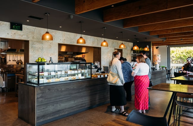 People waiting in line to be served inside a cafe.