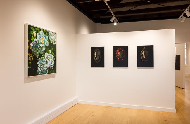 Paintings on two walls inside a large gallery space.