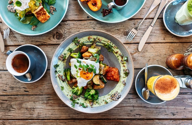 A flatlay of colourful plates of food and coffee.
